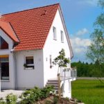 Ein Haus direkt an einem Feld im Sonnenschein mit Baum