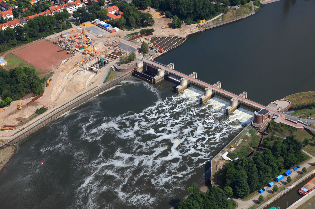 Luftaufnahme eines Wasserkraftwerks im Bau mit Staumauer und Baumaschinen im Hintergrund